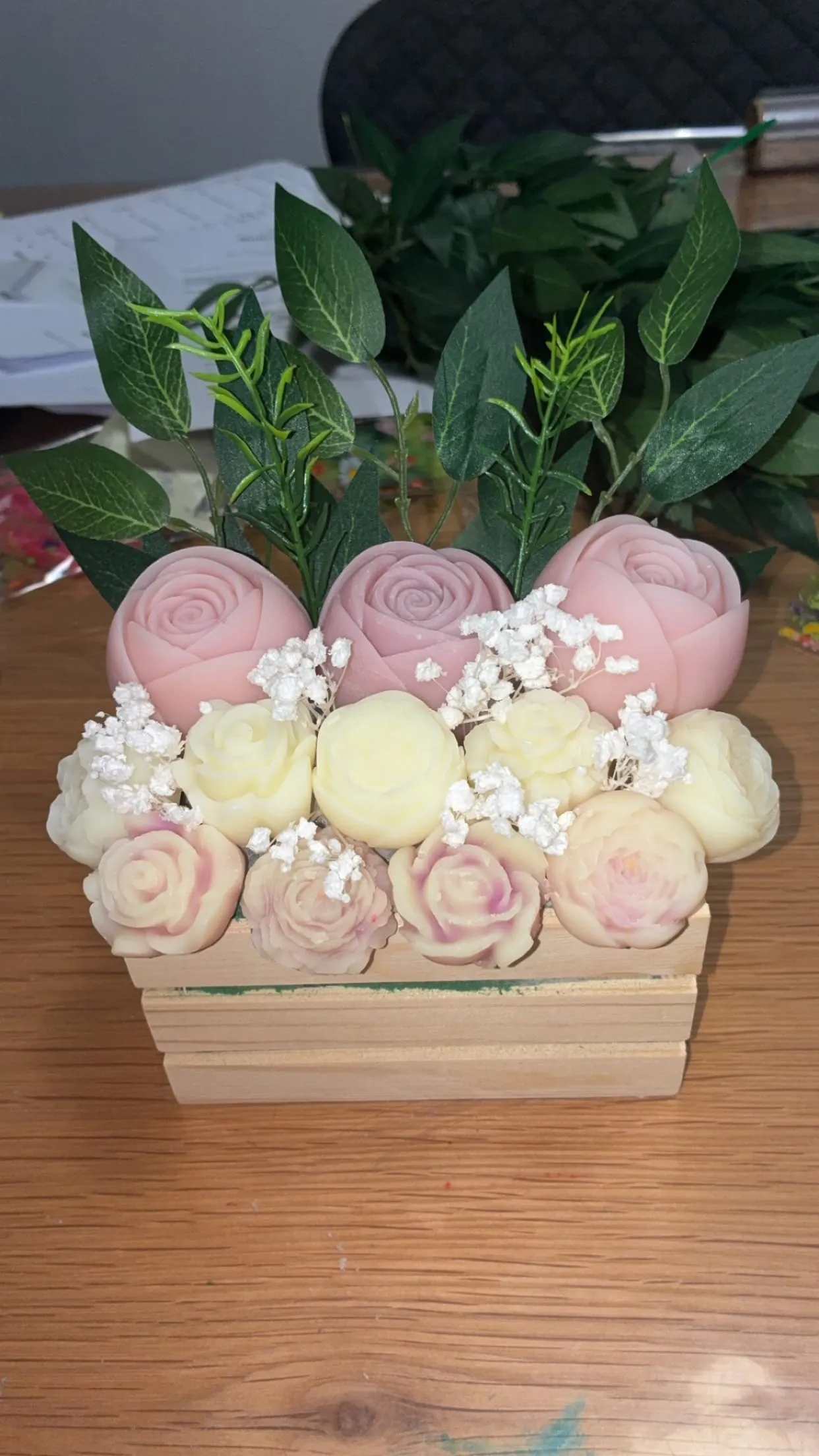 Bouquet de roses de cire roses et ivoire dans une caisse en bois, avec feuillage