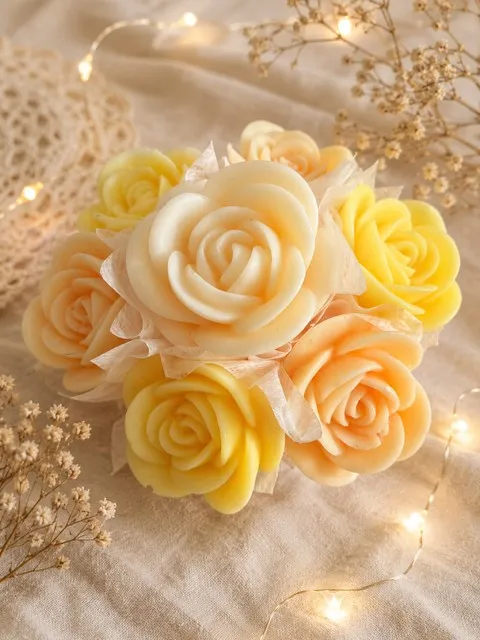 Bouquet rond de fleurs de cire en camaïeu jaune et pêche, sur un tissu clair avec guirlande lumineuse