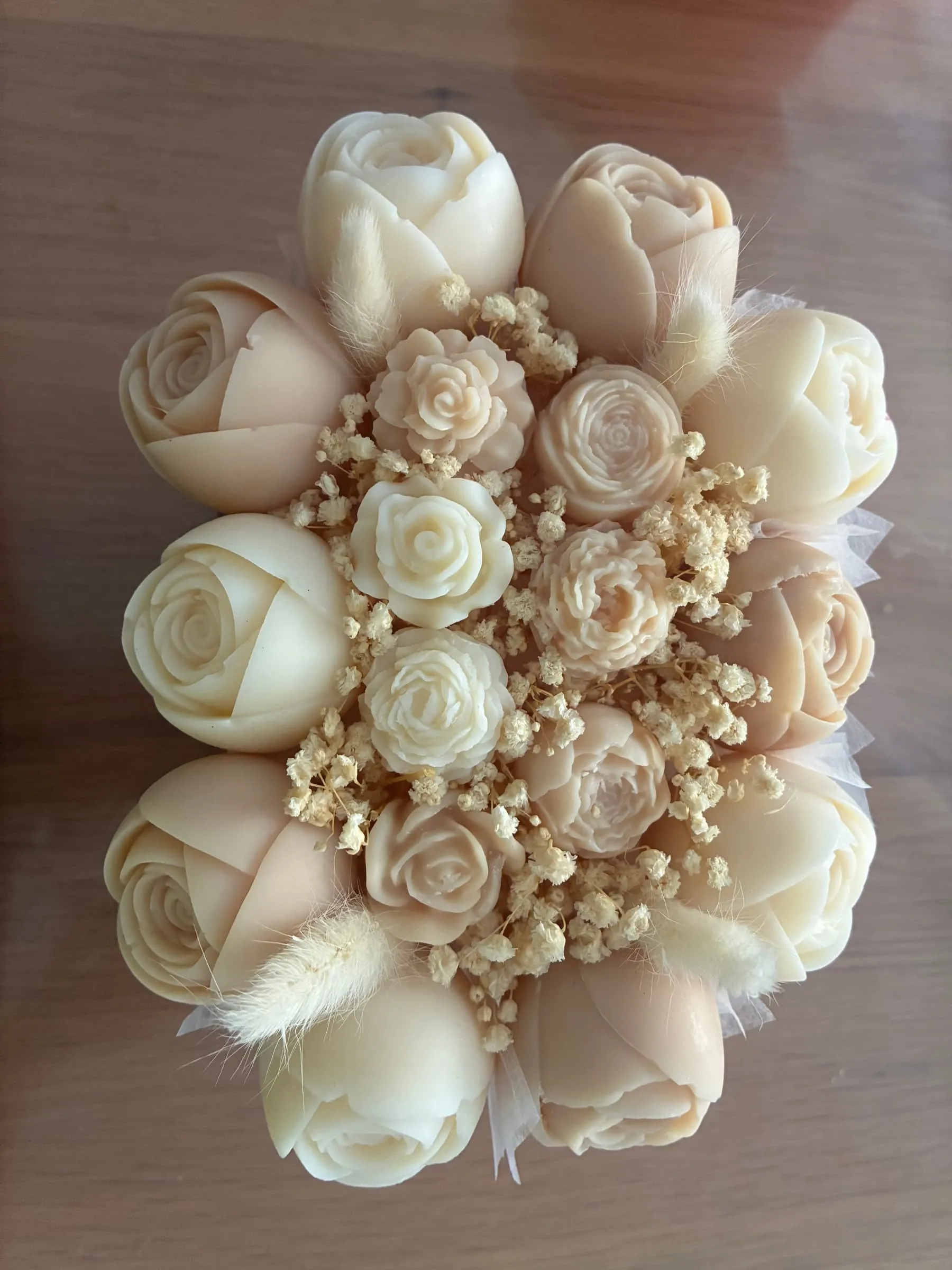 Bouquet de fleurs de cire entièrement ivoire et crème avec gypsophile, posé sur une table en bois