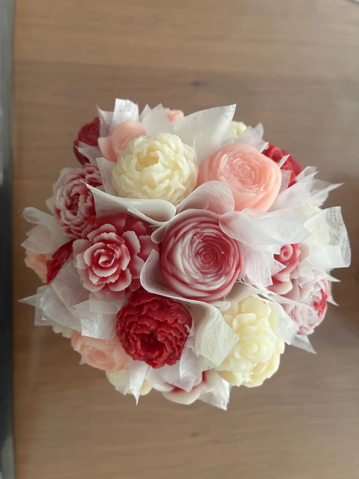 Bouquet rond de fleurs de cire en camaïeu rose et rouge, avec ruban blanc