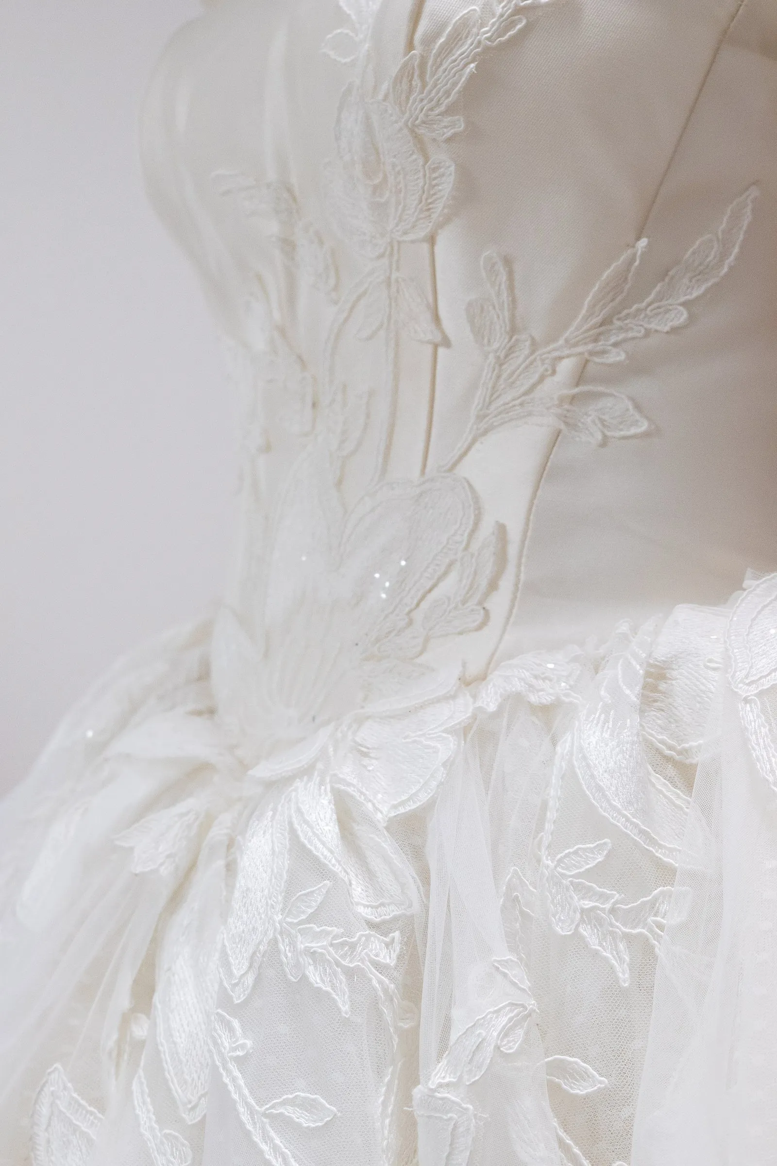 Détail de dentelle brodée sur un buste de robe de mariée, dressée sur mannequin