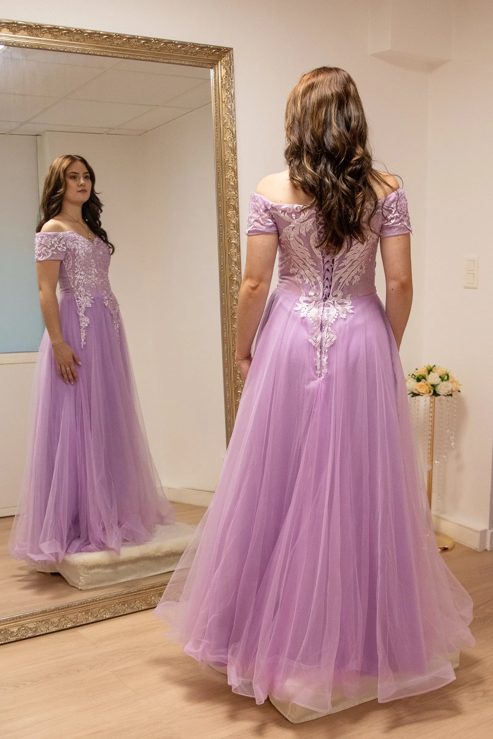 Robe de cérémonie mauve en tulle, vue de dos face au grand miroir doré de la boutique