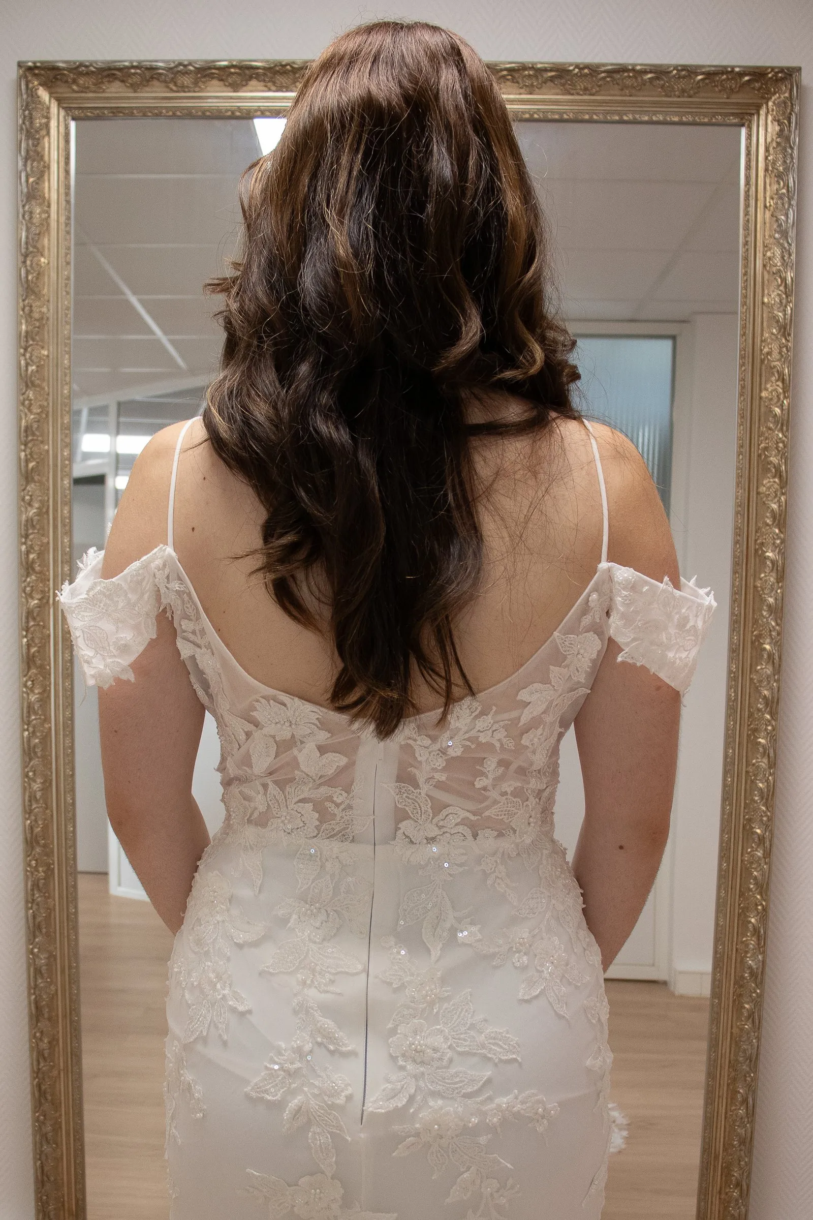 Robe de mariée sirène en dentelle, vue de dos face au grand miroir doré de la boutique