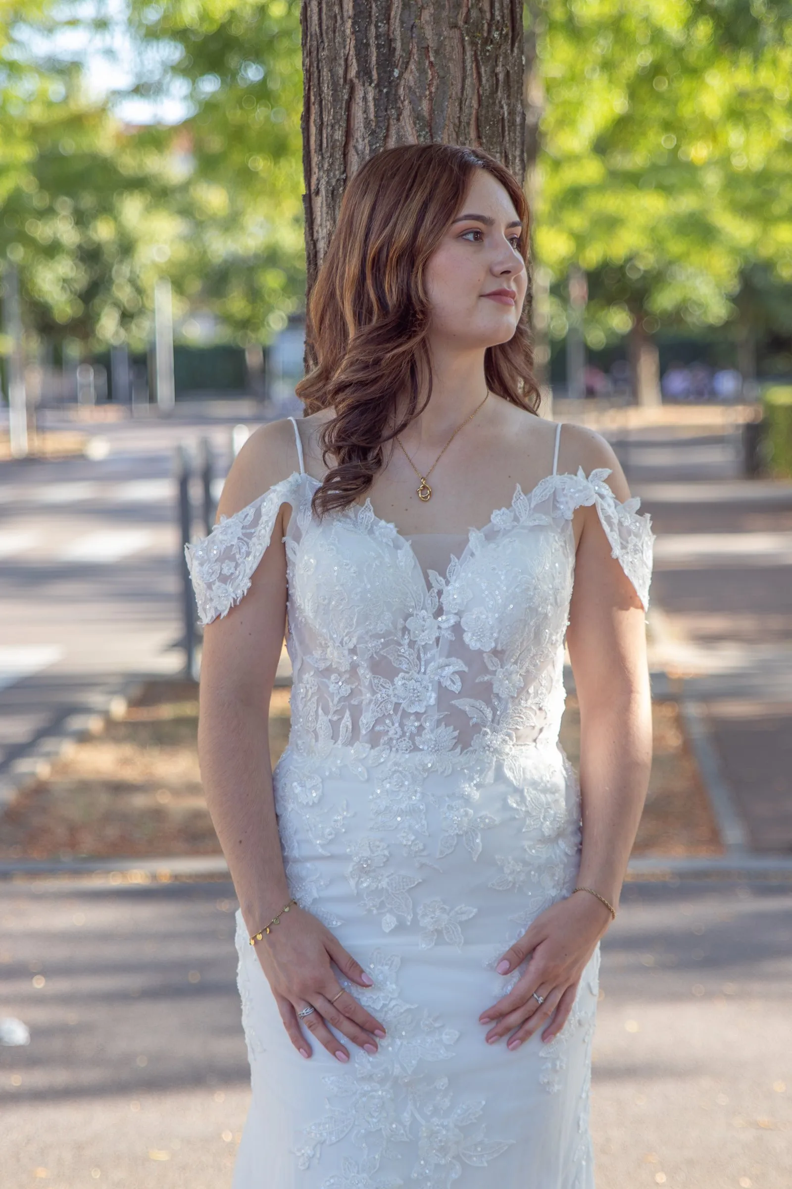 Robe de mariée sirène en dentelle, vue de face, essayage en extérieur devant un arbre